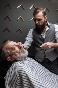 Old man getting his beard shaved by barber Stock Photos