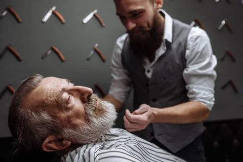 Old man getting his beard shaved by barber Stock Photos
