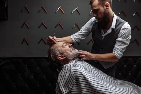 Old man getting his beard shaved by barber Stock Photos