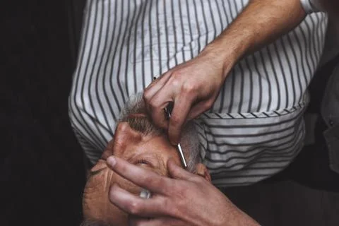 Old man getting his beard shaved by barber Stock Photos