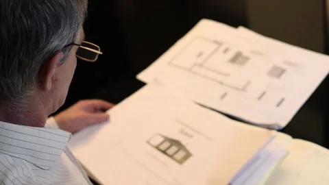 Old man in glasses moves stack of house plots on table. Slow motion Stock Footage 276369228