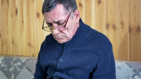 Old man with glasses sitting on a sofa, close-up Stock Footage 111490522