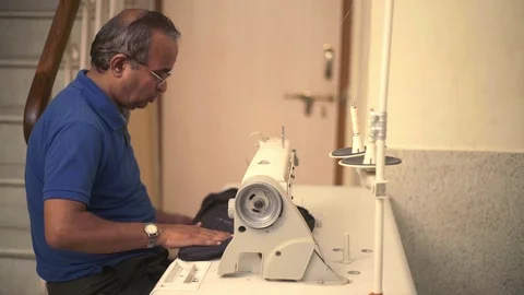 Old Man In Glasses Is Working As A Tailor On Sewing Machine. Stock Footage 113078311