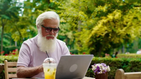 Old man good looking with a sunglasses working on his laptop in the middle of Stock Footage 164729782