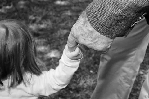 Old man hand while holding newborn infant in black and white Stock Photos