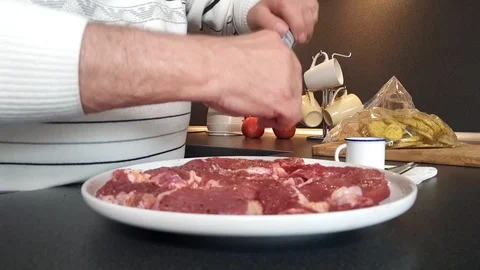 Old man hands pepper red meat fillets on plate at table Stock Footage 108605107