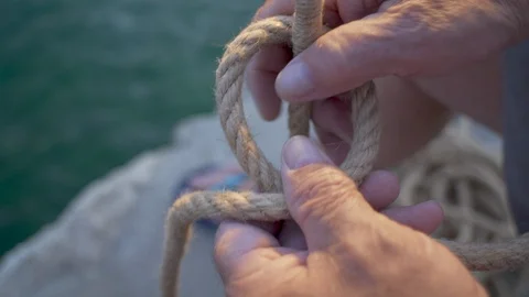 Old man hands tying Bowline knot with an old rope by the sea Stock Footage 94568851