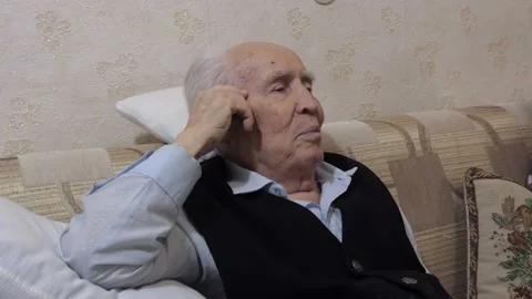 The old man is happily smiling on the couch, leaning on a pillow. Stock Footage 154983397