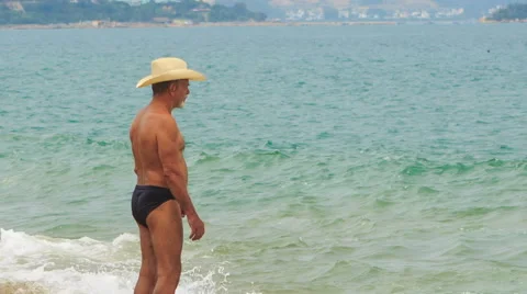 Old Man in Hat Stands by Foamy Wave Looks at Sea Vidéo 62520795