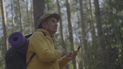 Old man holding compass tries to find way out of forest Stock Footage 244141130