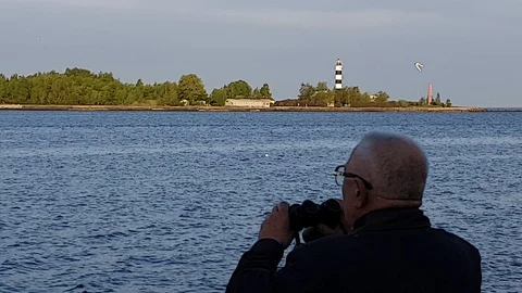 Old man holds binocular in hands and looks at opposite bank Stock Footage 110783841