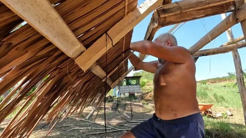 An old man installing native roof Stock Footage 277673159