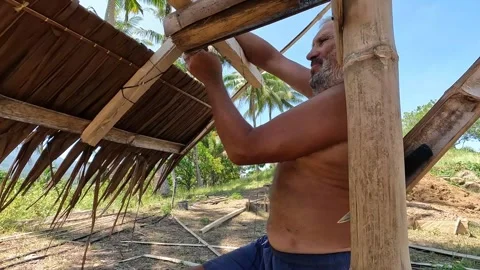 Old man installing roof using coconut palm Stock Footage 277673156