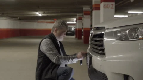 Old man installs vehicle identification number on parking site Stock Footage 328632524