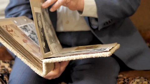 Old man leafs through an album with old black-and-white photographs Stock-Footage 124648044