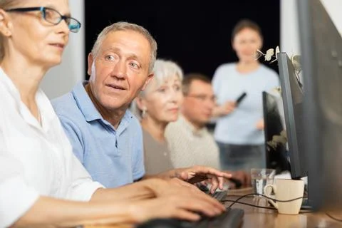 Old man learning computer programs and teacher speaking on the background Stock Photos