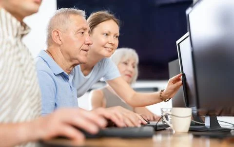 Old man learning computer programs with teacher in training room 写真素材