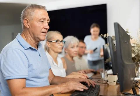 Old man learning computer programs and teacher speaking on the background Stock Photos