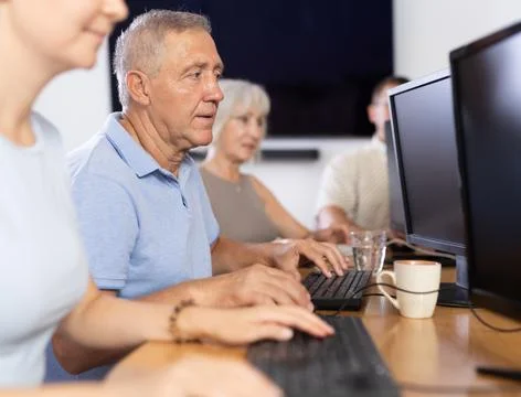 Old man learning computer programs in training room Fotos de archivo