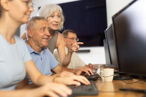 Old man learning computer programs with teacher in training room Foto stock