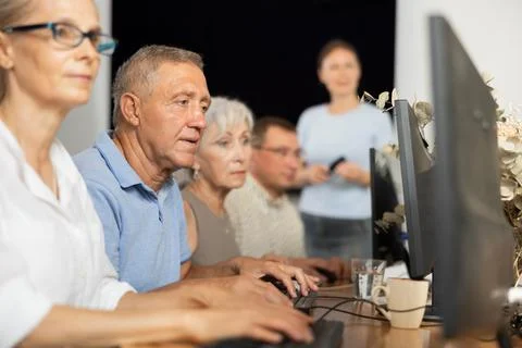 Old man learning computer programs and teacher speaking on the background 写真素材