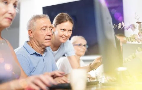 Old man learning computer programs with teacher in training room Foto stock