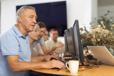 Old man learning computer programs in training room Fotos de archivo