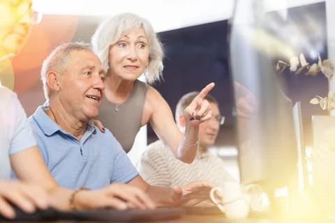 Old man learning computer programs with teacher in training room Stock Photos