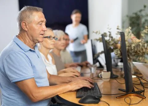 Old man learning computer programs and teacher speaking on the background Stock Photos