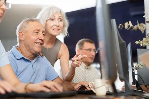 Old man learning computer programs with teacher in training room Stock Photos