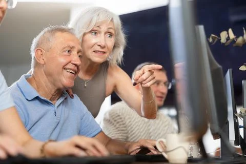 Old man learning computer programs with teacher in training room Stock-Fotos