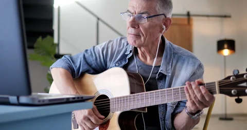 Old man learning to play guitar watching tutorial on laptop Video stock 138937478