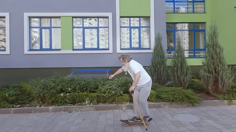 An old man is learning to ride a skateboard. Stock Footage 249545593