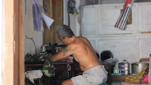 Old man learns to sew torn pants Stock Footage 282065543