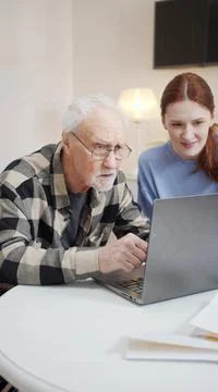 Old man learns to use computer while granddaughter helps him Stock Photos