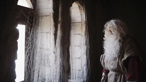 An old man with long white beard in red robe look into the window outside the Video stock 97813464