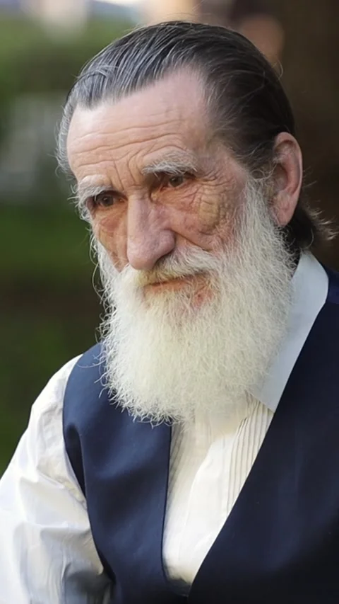 Old man with long white beard sitting on park bench with thoughtful expression Stock Footage 312188498