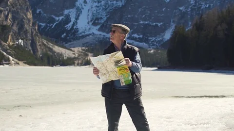 Old Man looking at map with lake and mountains on background Stock Footage 75790327