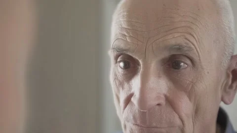 Old man looking in mirror and puts on blue medical facemask on his face. Stock Footage 147981938