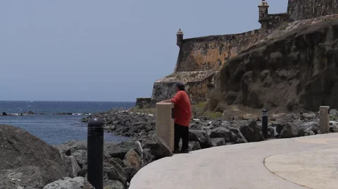 Old man looking at the sea standing on a waterfront sidewalk next to fortress Stock Footage 40363199