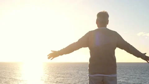 Old man looking to the sunset and the sea with opened arms feeling free and happ Stock Footage 151333224
