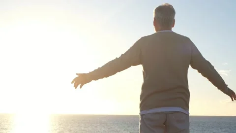 Old man looking to the sunset and the sea with opened arms feeling free and happ Stock Footage 151333346