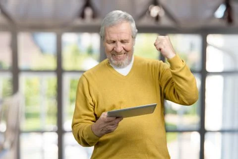 Old man looking at tablet and rejoicing. Stock Photos