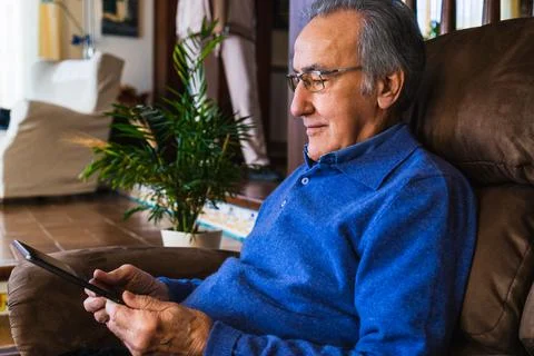 Old man looking at tablet in sofa Stock Photos