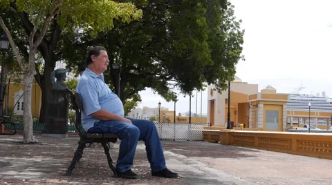 OLD MAN MAKES A CALL ON WATERFRONT PARK  BENCH with cell phone - Old San Juan Stock Footage 51345233