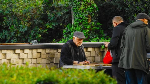 Old Man Moving Backgammon Pieces As Friends Look On Vídeos de archivo 348741577