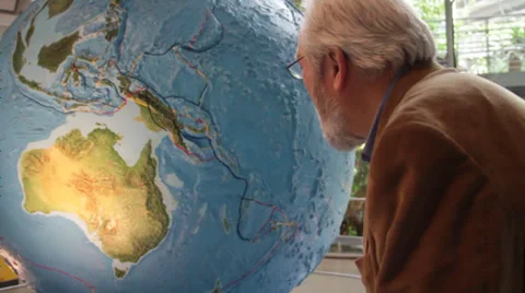 Old man in a museum lean in towrds globe Stock Footage 36150447