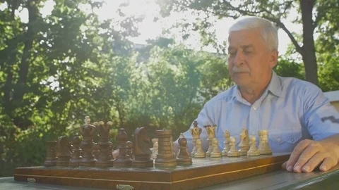 Old man opens the chess game with white pawn on E4 Stock Footage 118709536