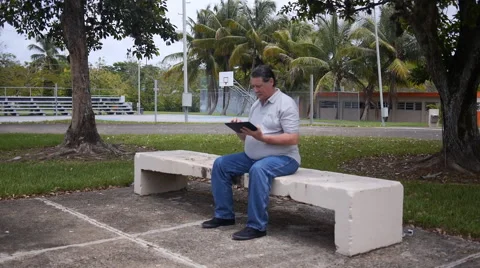 OLD MAN on park bench with Ipad-tablet looks at camera Stock Footage 51063709