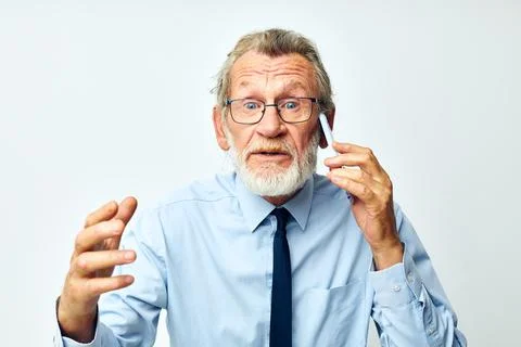 Old man with phone in studio on white background talking Stock Photos